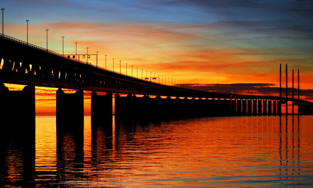 Øresundsbroen strækker sig over vandet ved solnedgang.